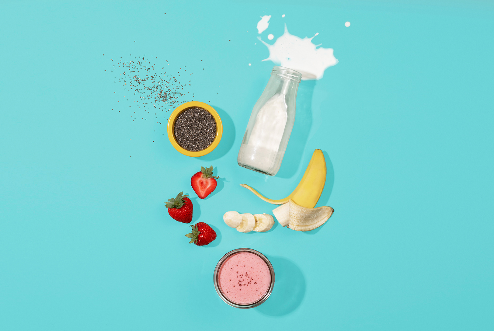 Chia seeds, strawberries, banana, milk, and a smoothie arranged flat lay.