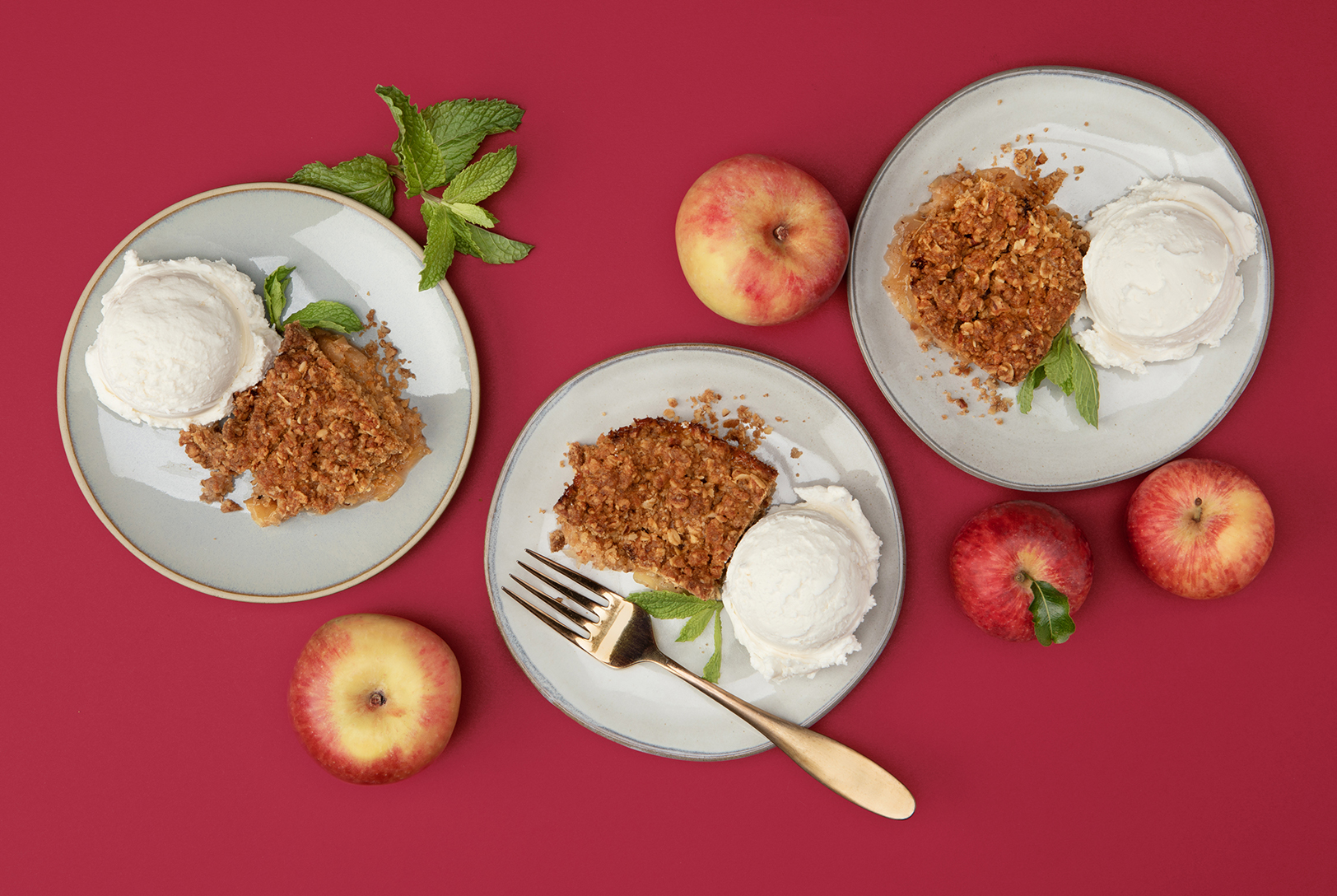 fresh apples and plates of apple crumble with vanilla ice cream 