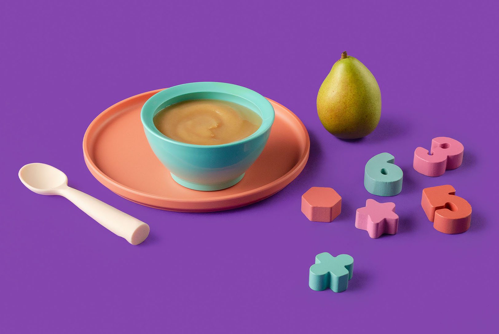 Baby bowl of pear puree with spoon and toys on outside