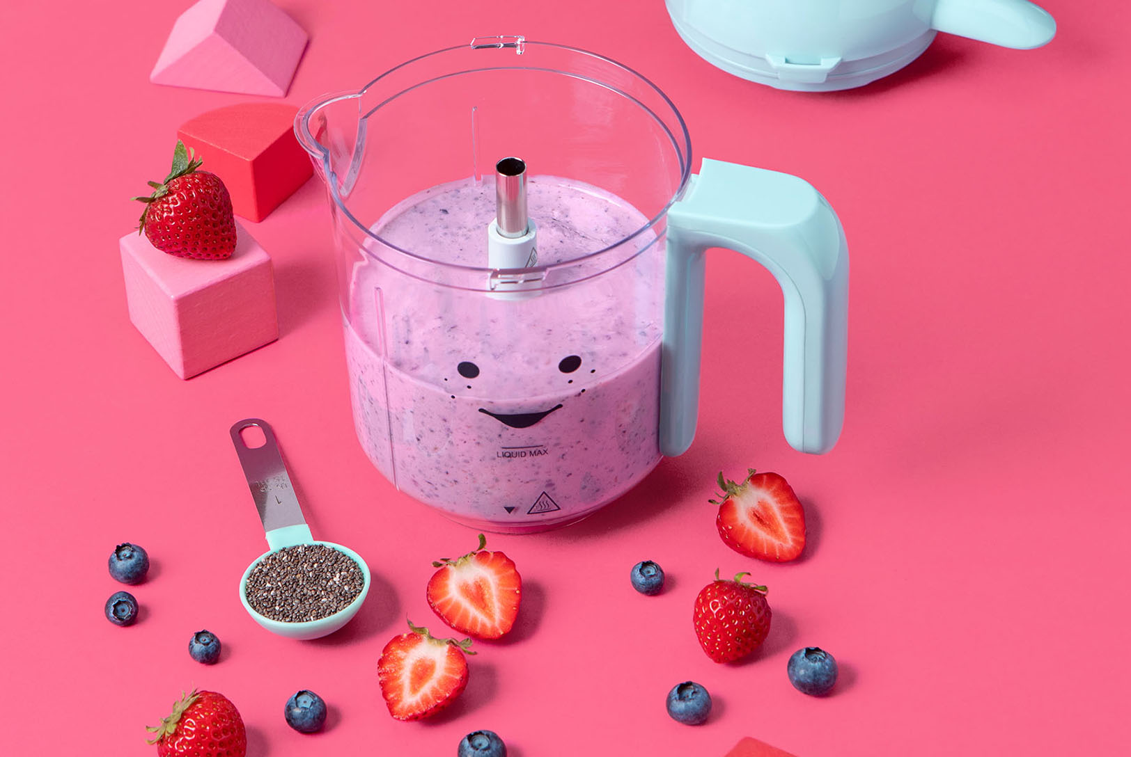 Blender with berries surrounding blender and tablespoon of chia seeds