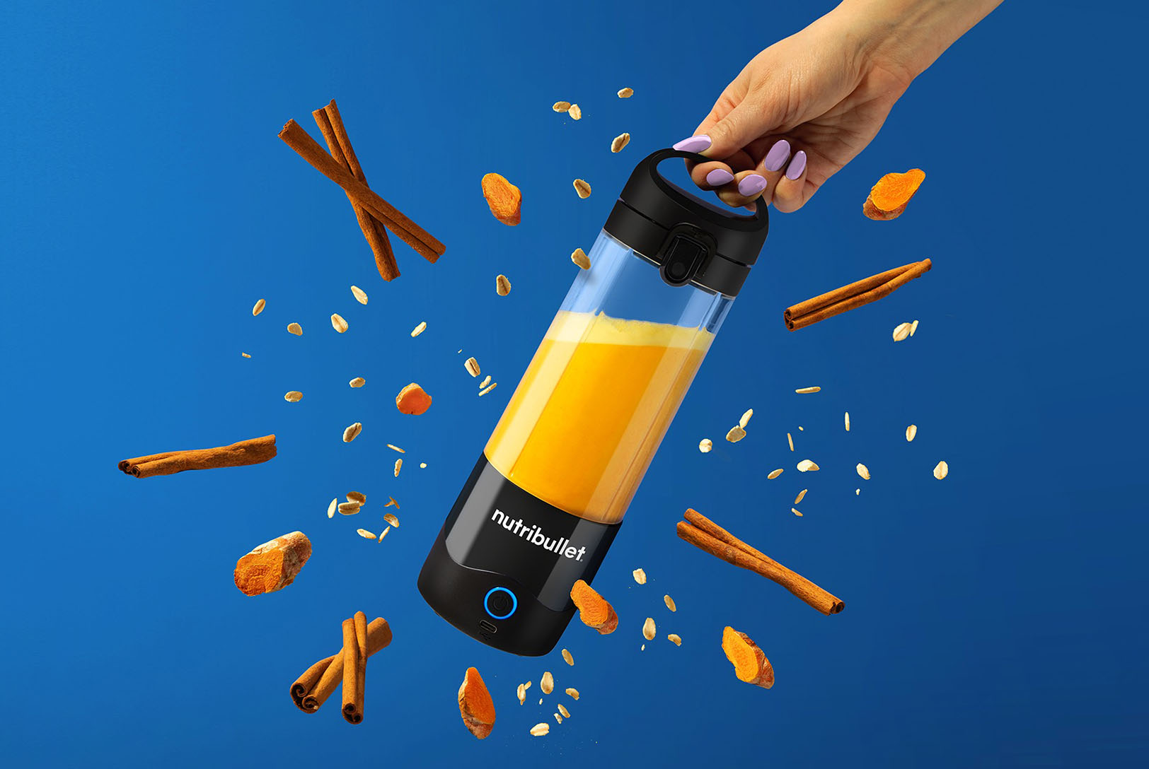 golden turmeric latte in portable magic bullet blender surrounded by cinnamon and spices 