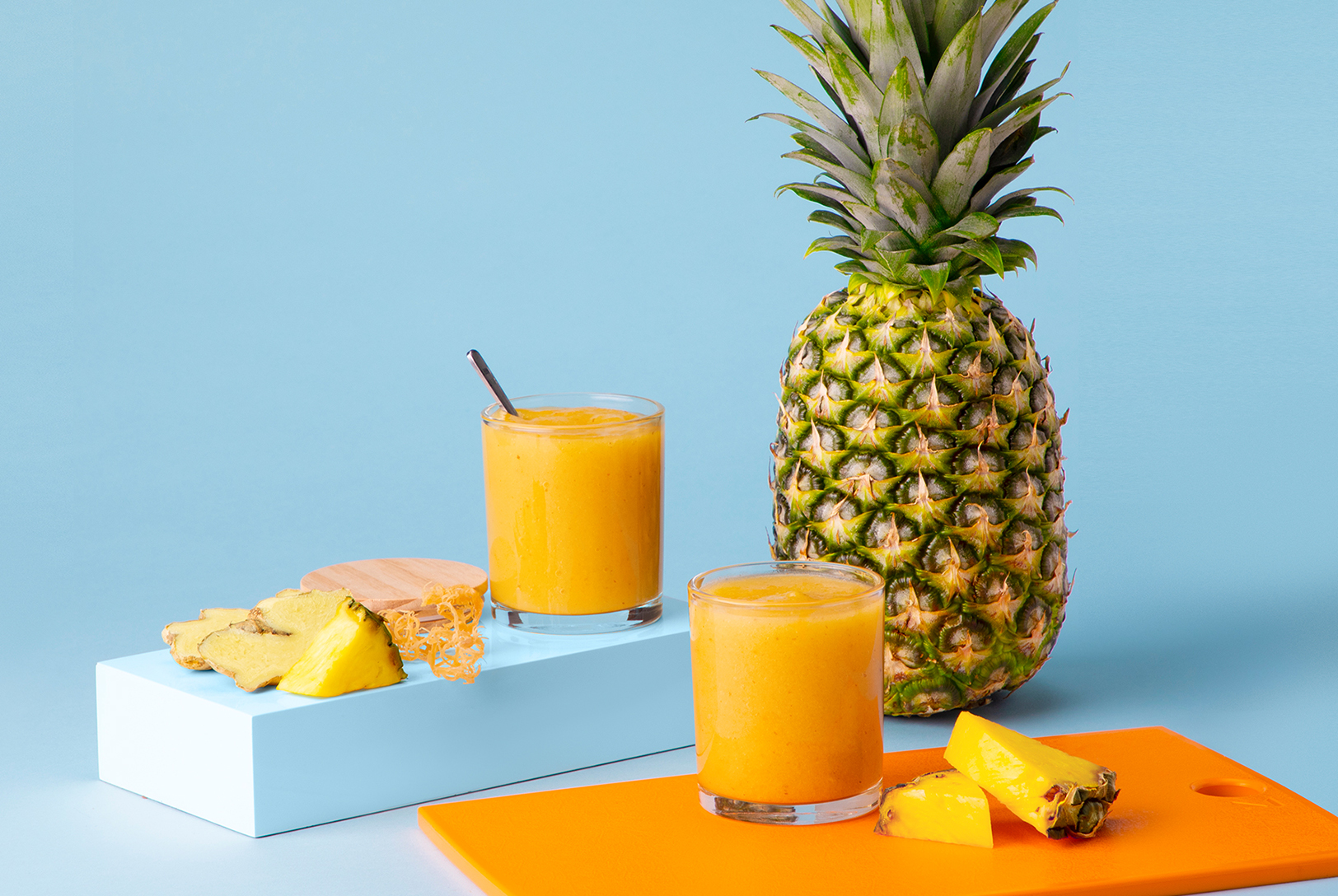 Pineapple Ginger Sea Moss Gel in two glasses with pineapple and orange cutting board