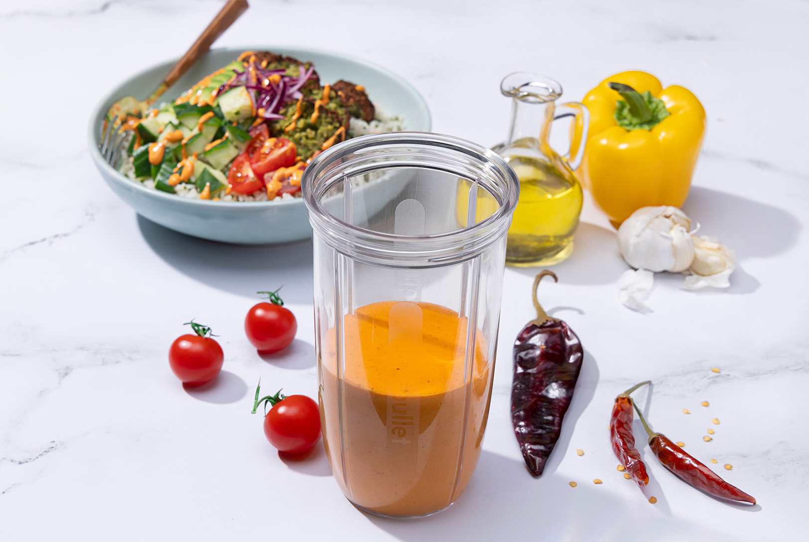 Creamy harissa dressing in a nutribullet cup alongside a salad and peppers