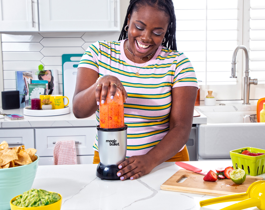 Woman in the kitchen making a smoothie on a magic bullet.