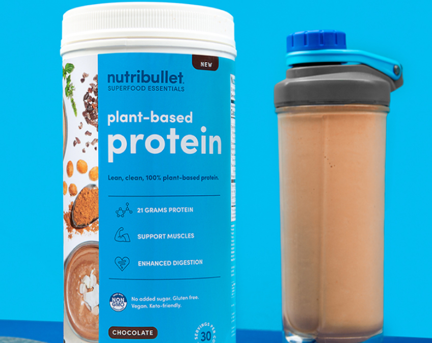 Blue tub of NutriBullet plant based protein and a bottle of brown smoothie on blue background.