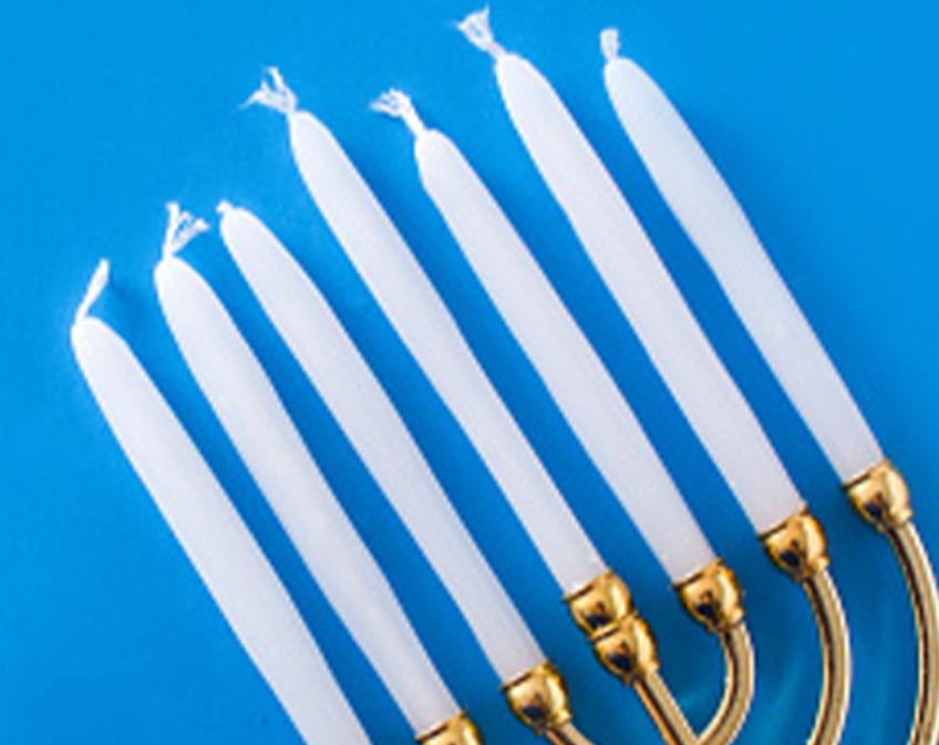 Gold menorah with white candles on blue background.