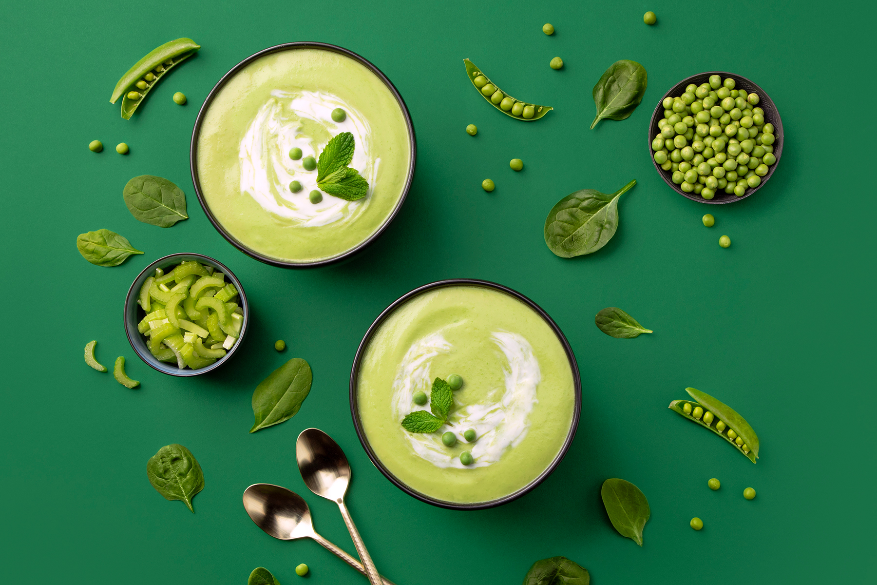 two bowls of green soup with peas, spinach, and celery