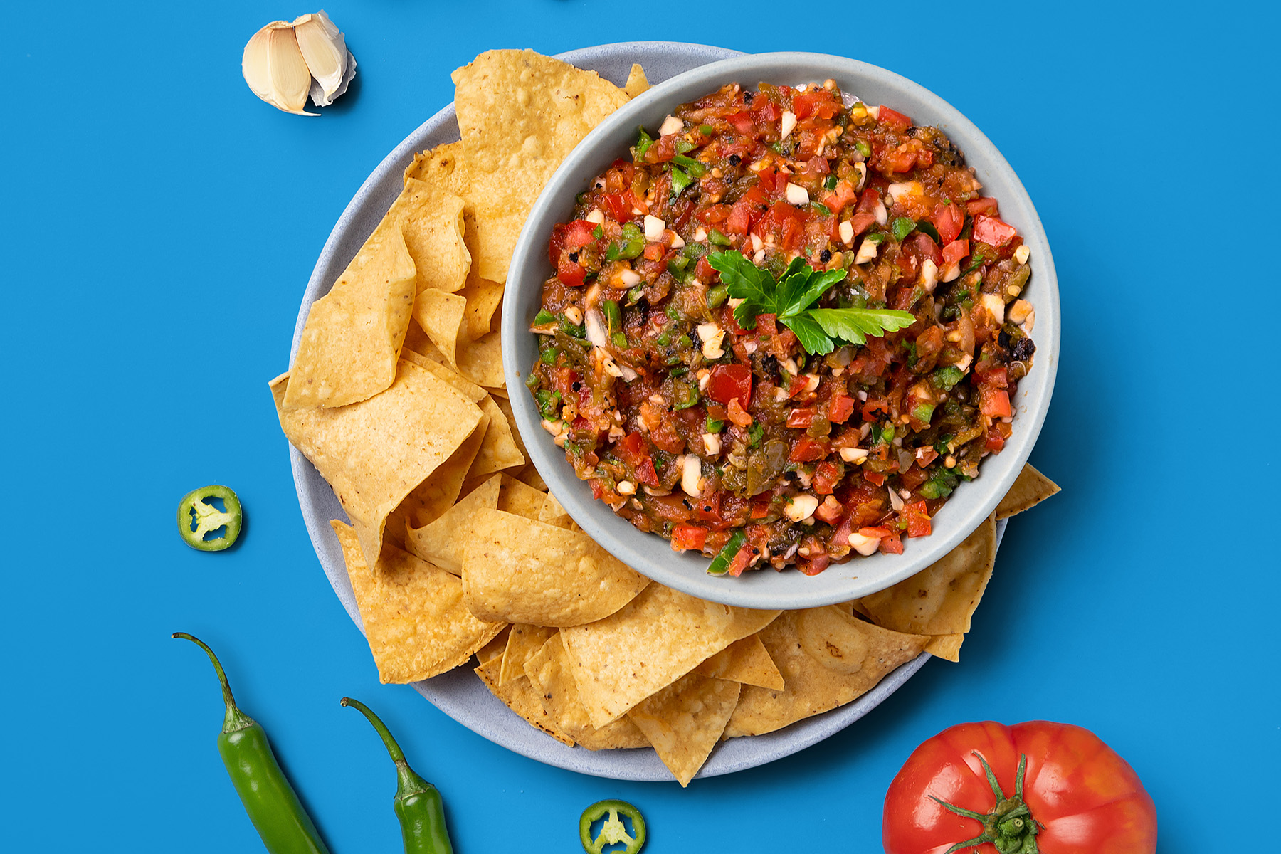salsa with tortilla chips garnished with herbs and jalapeño
