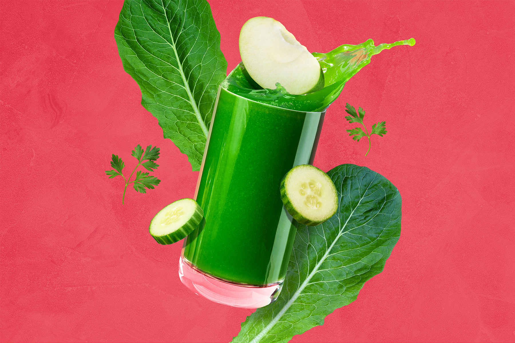 glass of green juice in front of red background