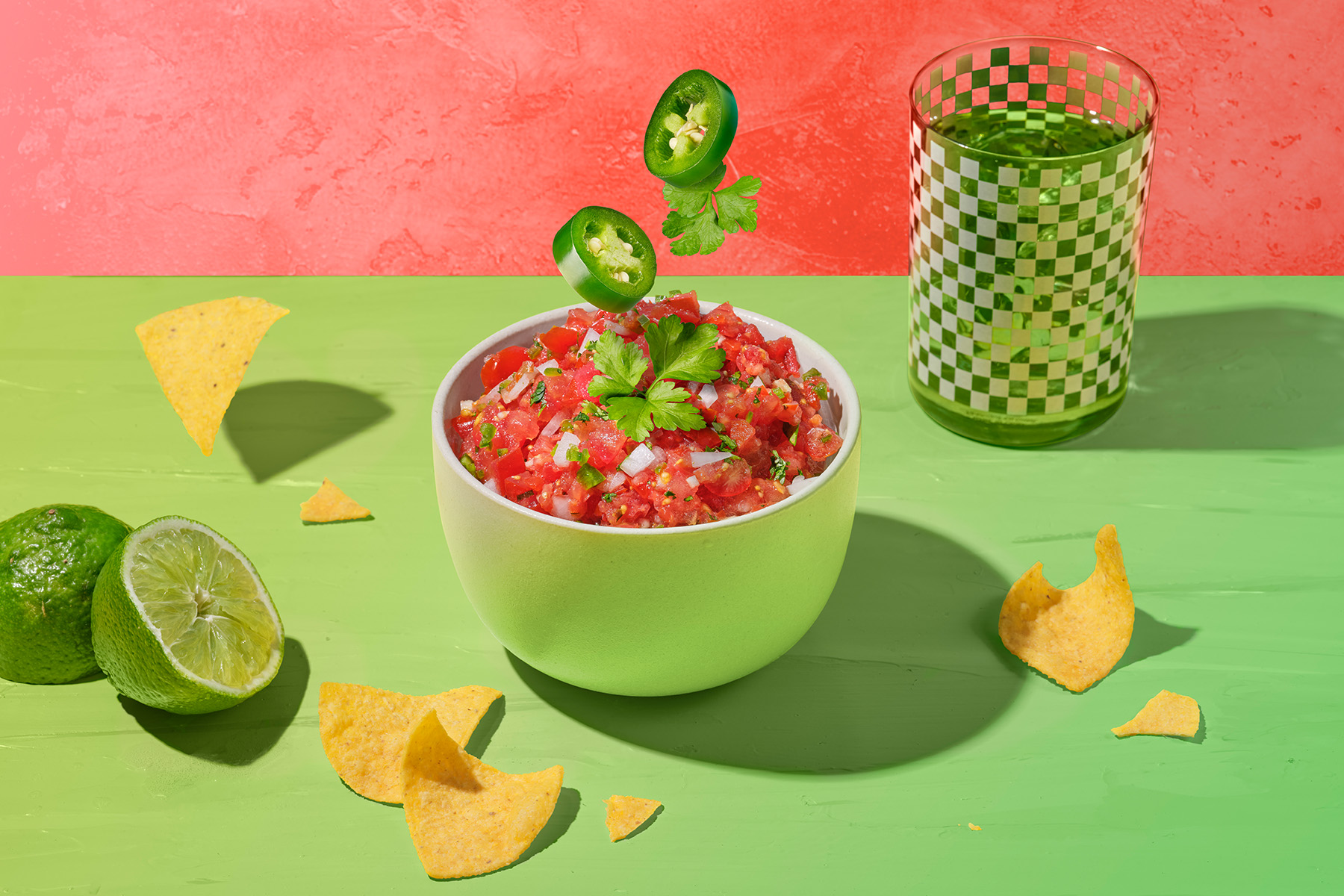 traditional salsa with cilantro and jalapeño garnish on green and orange background