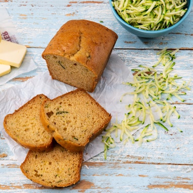 slices of spiced zucchini bread with butter, grated zucchini, and cinnamon sugar