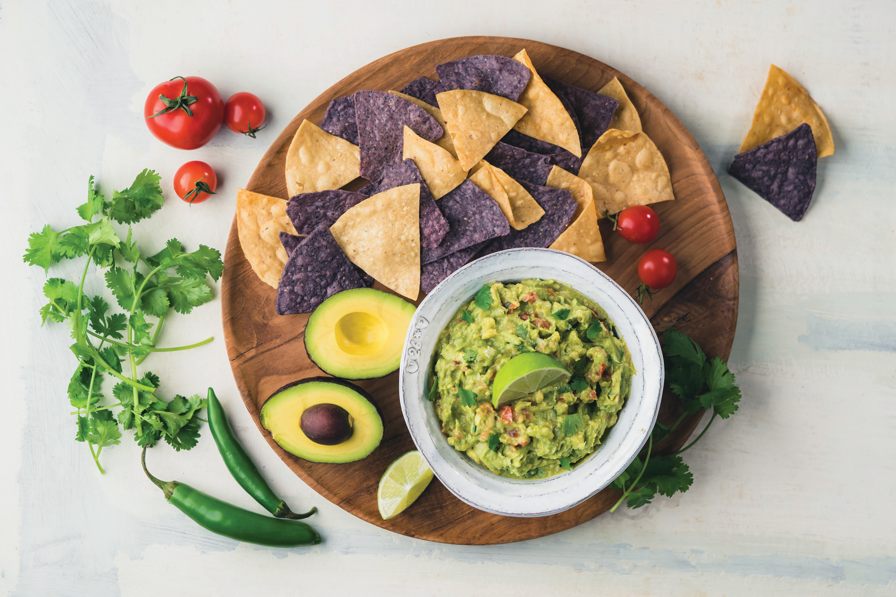 platter of guacamole with chips avocado tomato lime and cilantro