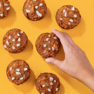 hand holding a pumpkin carrot muffin made with carrot juice pulp