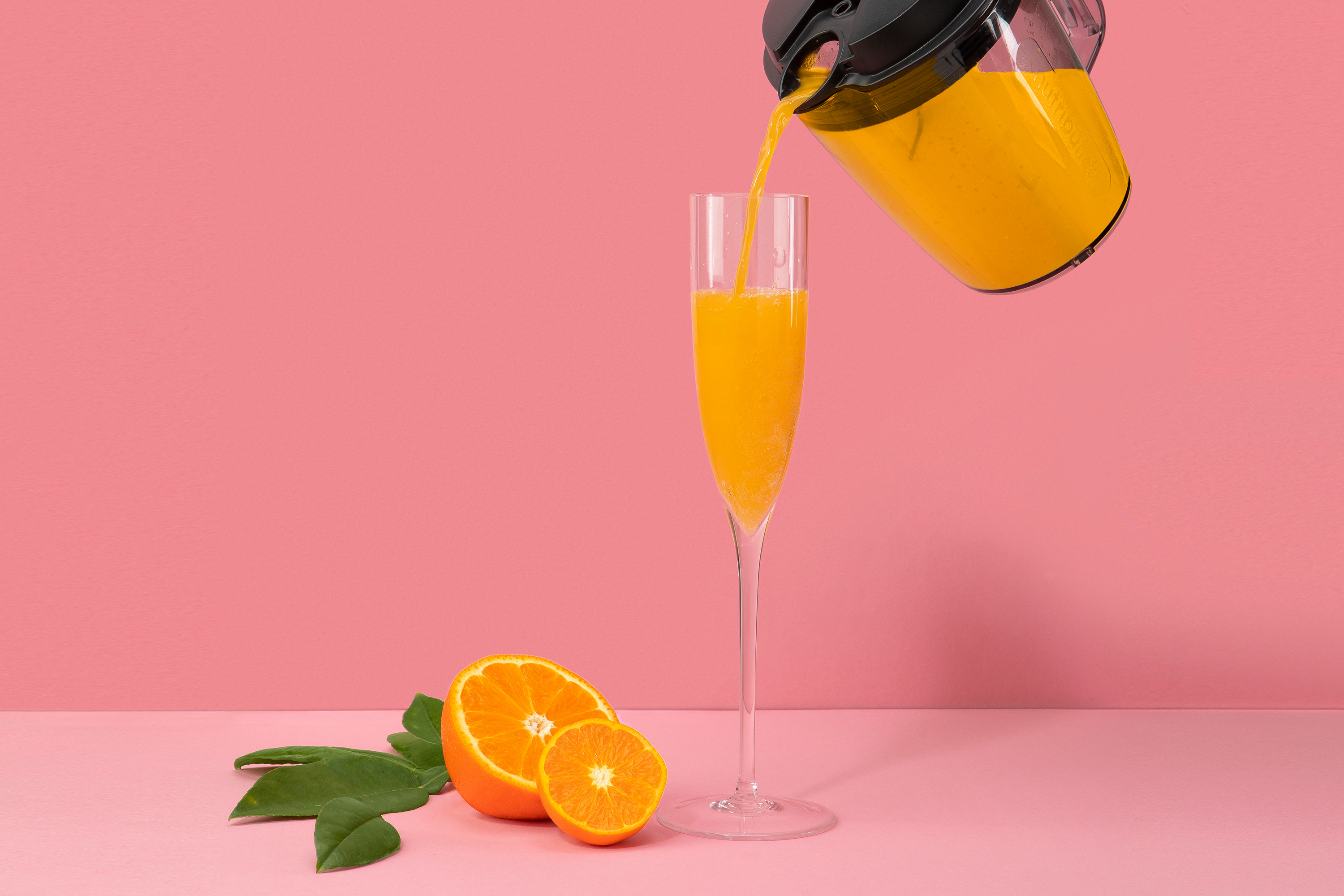 mimosa being pour into a glass with fresh oranges and clementine
