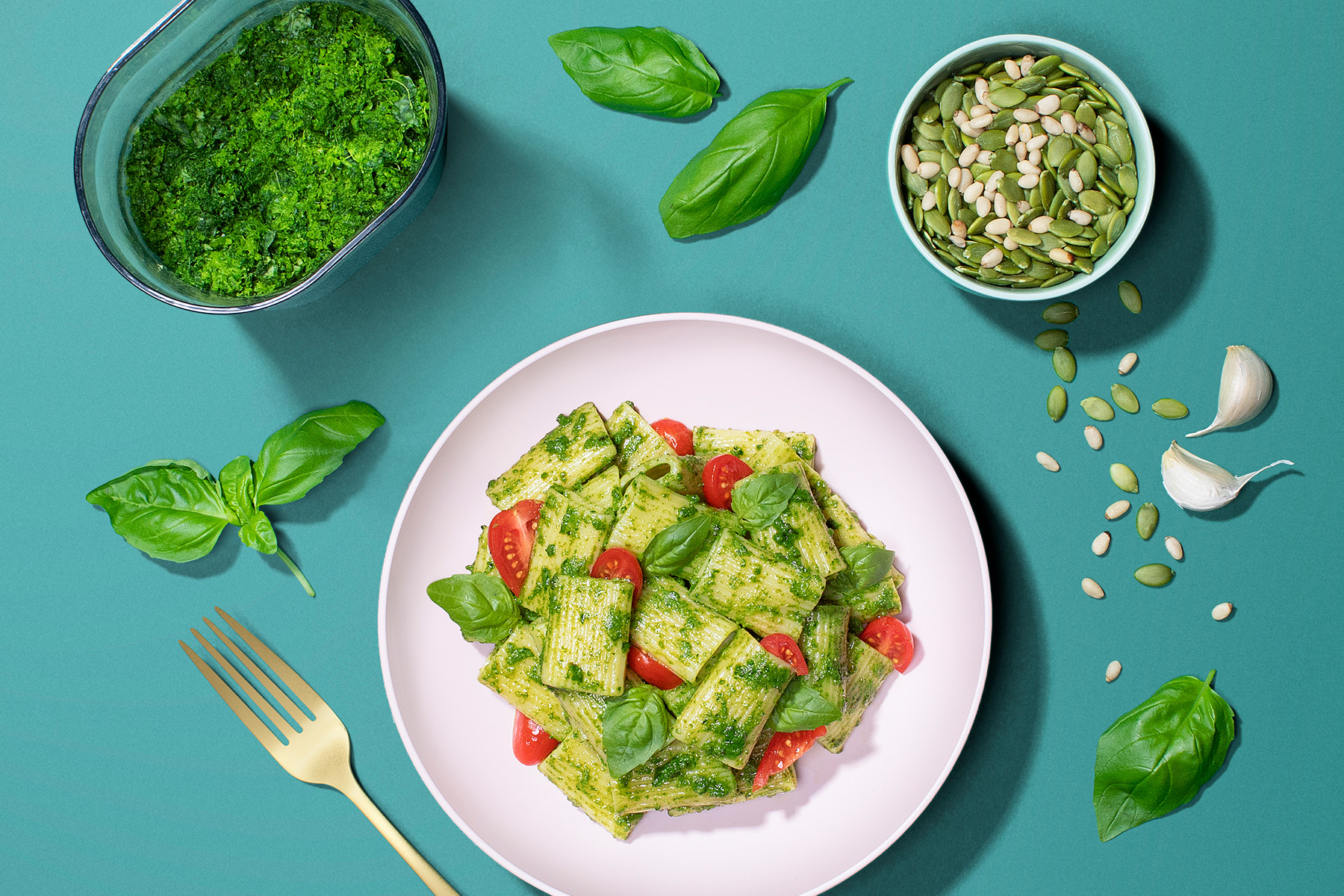 plate of pasta with pesto, basil, and cherry tomatoes with pesto ingredients