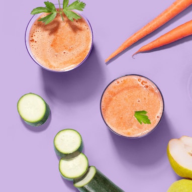 glasses of carrot juice with carrots, pears, and zucchini
