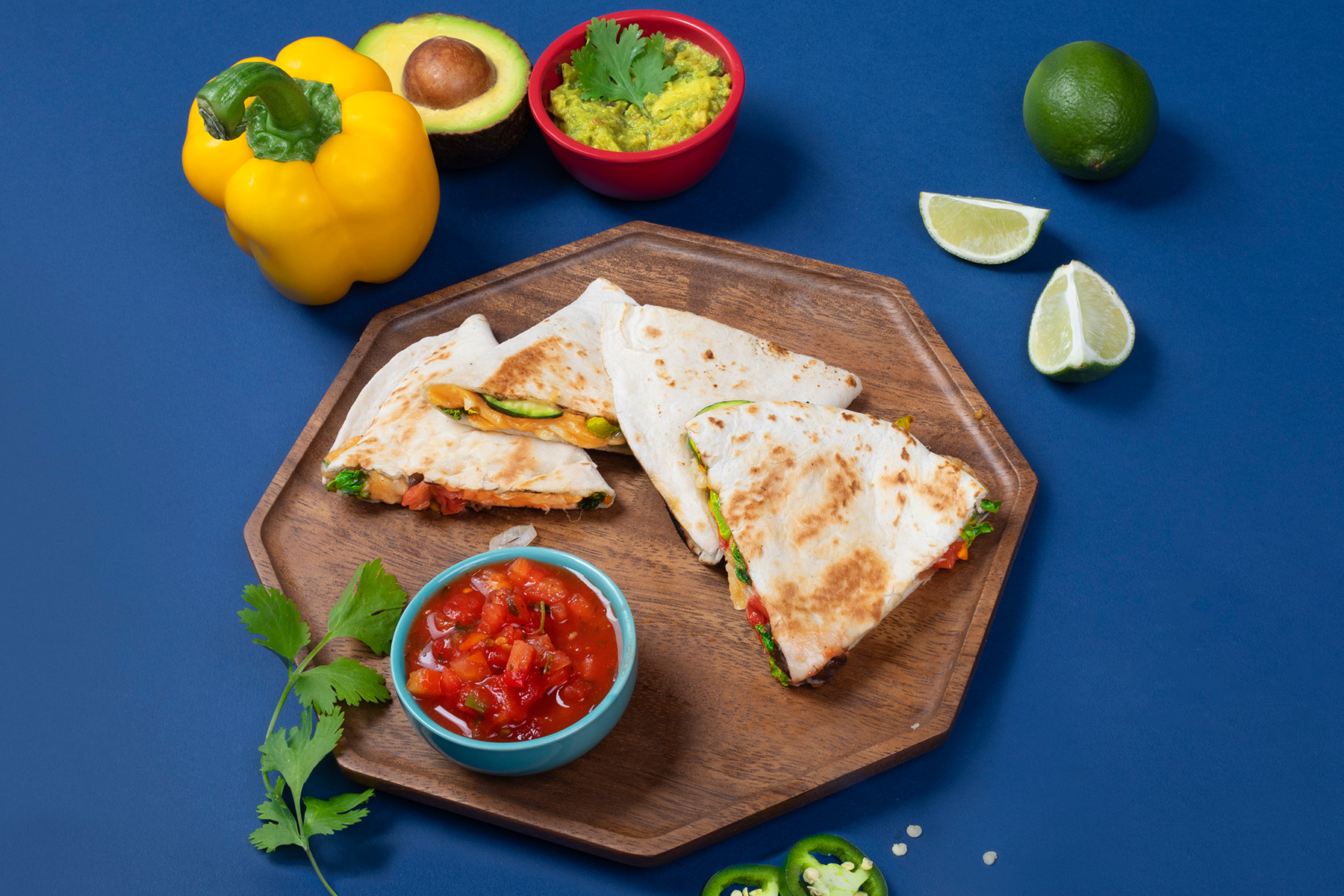 plate of vegetable quesadilla with salsa, guacamole, and lime wedges