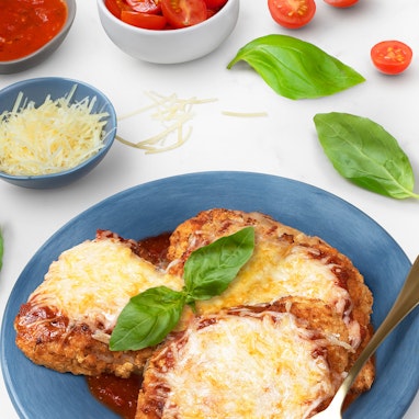 plate of chicken parmesan with basil and cherry tomatoes