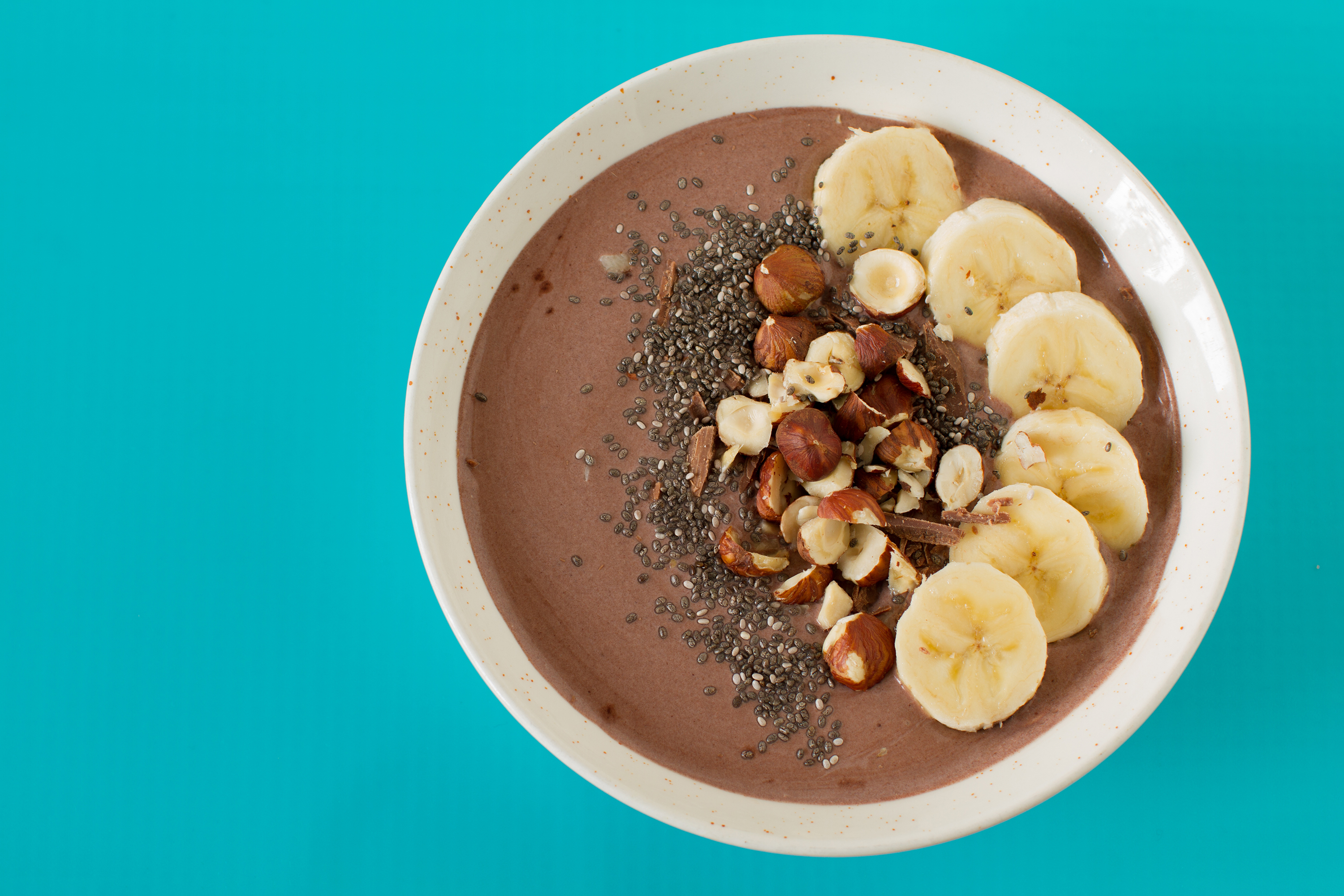 coffee smoothie bowl with banana slices, chia seeds, and chopped hazelnuts