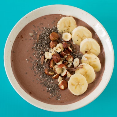 coffee smoothie bowl with banana slices, chia seeds, and chopped hazelnuts