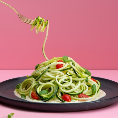 plate of zucchini noodles with cashew cream sauce, basil and cherry tomatoes